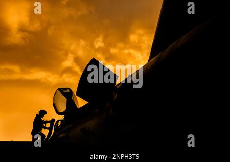 Le pilote de chasse monte à bord de son intercepteur de chasseur à réaction pour une mission d'entraînement au combat au coucher du soleil. Silhouette dramatique de pilote de héros se préparant à la guerre Banque D'Images