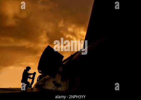 Le pilote de chasse monte à bord de son intercepteur de chasseur à réaction pour une mission d'entraînement au combat au coucher du soleil. Silhouette dramatique de pilote de héros se préparant à la guerre Banque D'Images