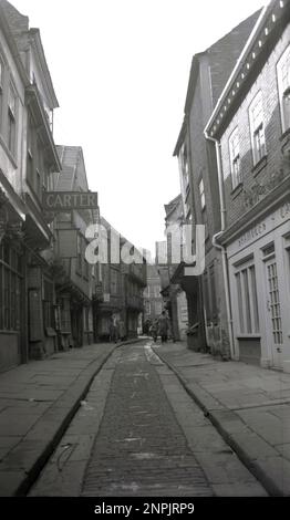 Années 1950, historique, une vue du niveau du sol, vers le haut de The Shambles, une ancienne rue pavée médiévale étroite à York, Angleterre, Royaume-Uni. Vu sur la photo un signe pour carter, une vieille boucherie établie. Le Shambles est connu comme la «rue des bouchers», le nom provenant du médiéval «shamel» ou stand, qui exposait de la viande à l'extérieur. Banque D'Images