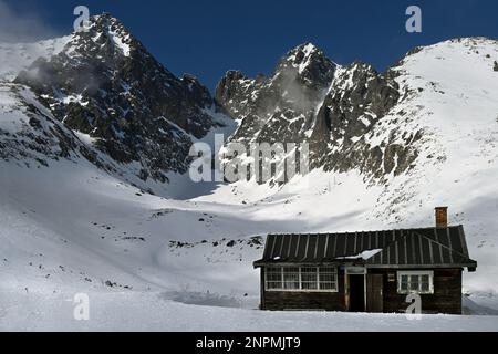 Cabane en bois près de Skalnaté Pleso, avec les pics Lomnický štít et Kežmarský štít dans la chaîne de montagnes Vysoké Tatry au-dessus de Tatranská Lomnica, Slovaquie Banque D'Images