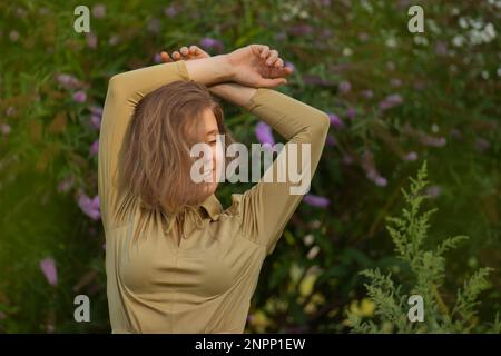 Femme dans les fleurs ensoleillées champ de la Buddleia. Bonne jeune fille dans le domaine. Banque D'Images