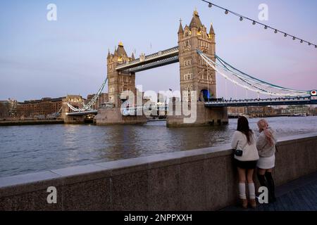 Touristes près de Tower Bridge en début de soirée lumière le 5th février 2023 à Londres, Royaume-Uni. Tower Bridge est un pont combiné de classe I à Londres, construit entre 1886 et 1894, conçu par Horace Jones et réalisé par John Wolfe Barry avec l'aide de Henry Marc Brunel. Banque D'Images