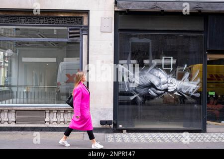 Fermeture des espaces de vente au détail avec des graffitis de rue de poing d'art sur Albemarle Street à Mayfair le 10th février 2023 à Londres, Royaume-Uni. Les choses ont été difficiles pour les petites entreprises au cours des deux dernières années et surtout maintenant avec la crise actuelle du coût de la vie et les pressions financières croissantes sur le coût des biens au cours desquelles les prix de nombreux biens essentiels au Royaume-Uni ont commencé à augmenter plus rapidement que les revenus des ménages, entraînant une chute des revenus réels. Cela est dû en partie à une hausse de l'inflation au Royaume-Uni, ainsi qu'à l'impact économique des questions étrangères. Banque D'Images