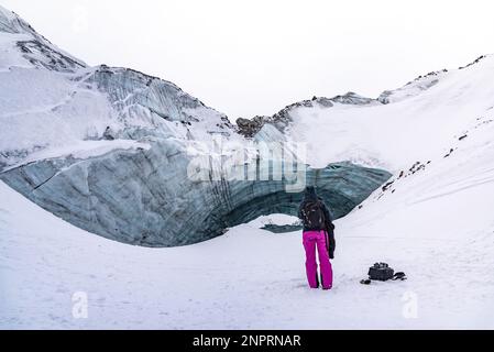 Femme debout à l'extérieur d'une belle grotte de glace dans le nord du Canada pendant l'hiver. Banque D'Images