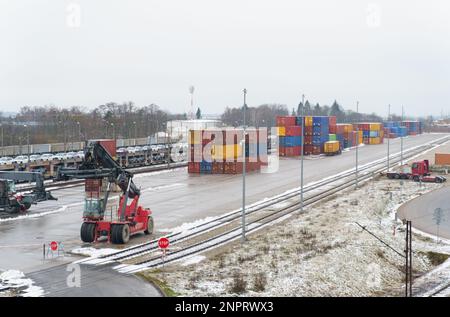 Le chargeur se tient sur le site en attendant le déchargement ou le chargement des conteneurs à la station. Chemin de fer en attente du terminal de distribution de marchandises. Banque D'Images