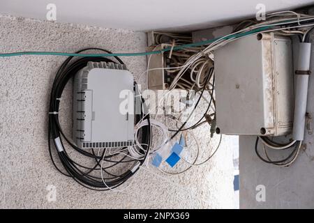 Concentrateur réseau fibre optique sur le mur et câbles TV anciens dans une boîte en plastique. connexion haut débit en israël vieux concept de bâtiment. Banque D'Images