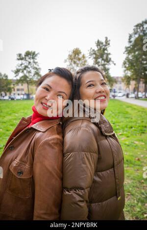 Deux femmes asiatiques souriantes et amicales se posent de nouveau dans un parc public Banque D'Images