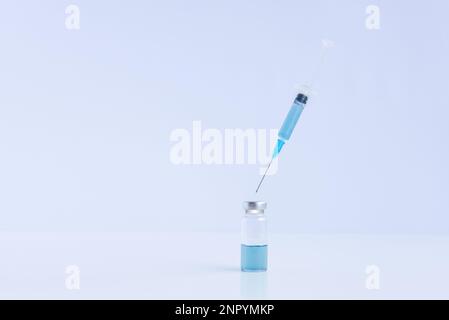 Sur fond blanc isolé, flacon en verre transparent avec vaccin bleu contre les virus avec seringue jetable. Lutte contre les épidémies d'infection. Co Banque D'Images