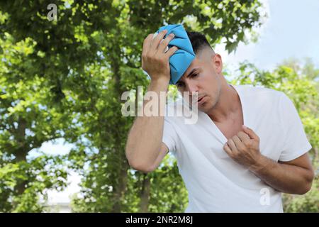 Homme avec le bloc froid souffrant de coup de chaleur à l'extérieur Banque D'Images