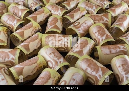 Vue de dessus des billets de cent dollars canadiens en rouleau avec le portrait du Premier ministre du Canada Sir Robert L. Borden sur fond noir. Banque D'Images