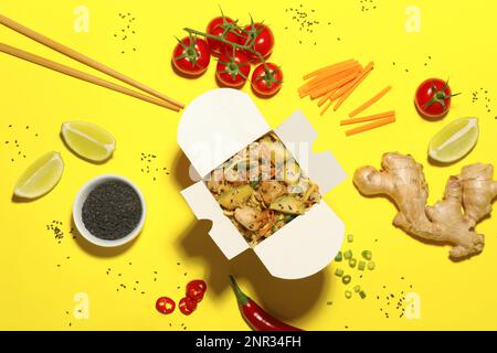 Composition à plat avec wok de nouilles et ingrédients sur fond jaune Banque D'Images