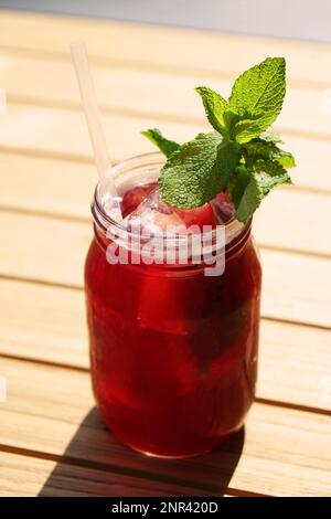 thé glacé aux myrtilles servi dans un pot en verre avec des feuilles de menthe fraîche et de la paille à boire Banque D'Images