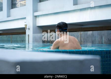 Vue arrière de l'homme dans la piscine, se détendre sur le côté. Concept de vacances ou de voyages. Banque D'Images