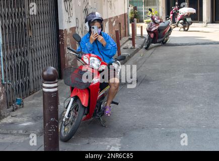 SAMUT PRAKAN, THAÏLANDE, 04 2023 FÉVRIER, Une femme est assise sur une moto garée et parle au téléphone Banque D'Images