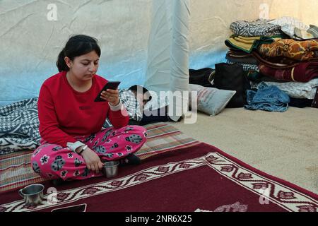 Diyarbakir, Turquie. 26th févr. 2023. Zelal est vu regarder les nouvelles au téléphone. Au total, 4 200 tentes seront mises en place dans 2 centres pour les victimes du tremblement de terre à Diyarbakir. L'installation de 1800 tentes a été achevée et elles ont été offertes aux familles des victimes du tremblement de terre. Dans les tentes, les besoins des familles des victimes du tremblement de terre comme la nourriture, les toilettes, la salle de bains, l'éducation, les sports, la santé et le culte sont respectés. Crédit : SOPA Images Limited/Alamy Live News Banque D'Images