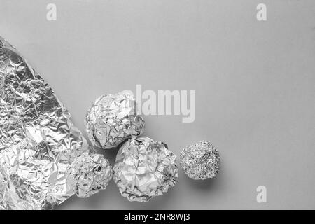 Boules de papier aluminium froissé sur fond gris Banque D'Images