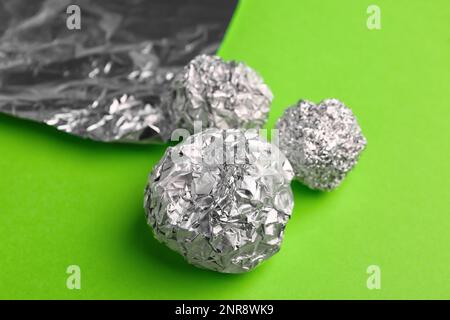 Boules de feuilles d'aluminium froissés sur fond vert, gros plan Banque D'Images