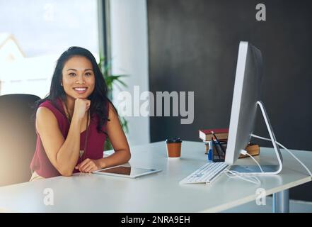 Le travail acharné est si gratifiant. Portrait d'une jeune femme d'affaires confiante assise à un bureau dans un bureau moderne. Banque D'Images