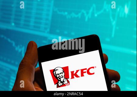 15 février 2023, Chine : dans cette illustration, le logo de la chaîne de restauration rapide américaine Kentucky Fried Chicken (KFC) est affiché sur un smartphone avec un graphique d'indice boursier en arrière-plan. (Credit image: © Budrul Chukrut/SOPA Images via ZUMA Press Wire) USAGE ÉDITORIAL SEULEMENT! Non destiné À un usage commercial ! Banque D'Images