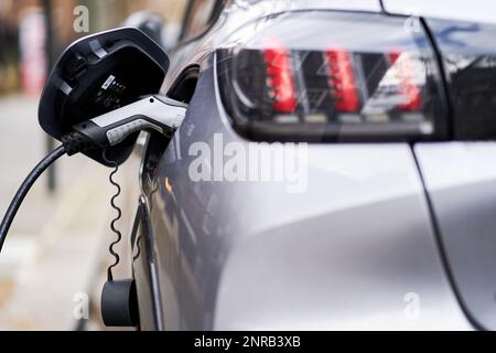 Photo du dossier daté du 05/03/21 d'une voiture électrique Peugeot branchée dans un point de charge de VE, comme une loi obligeant les fabricants à vendre une proportion de plus en plus grande de véhicules électriques chaque année aiderait les conducteurs à économiser des milliards de livres sur la durée de vie de leurs voitures, de nouvelles analyses ont affirmé. Banque D'Images