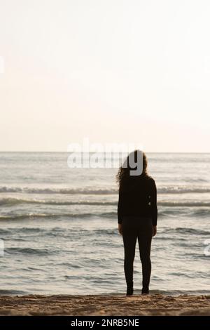 Jeune femme debout sur la plage Banque D'Images