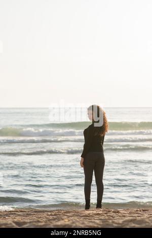 Jeune femme debout sur la plage et regardant sur l'épaule Banque D'Images