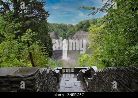 Taughannock Falls par une journée ensoleillée, entouré de rochers et d'arbres, le cours d'eau se vidant dans une piscine. Escaliers descendant au premier plan. Banque D'Images