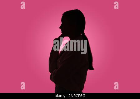Silhouette de femme anonyme sur fond rose Banque D'Images