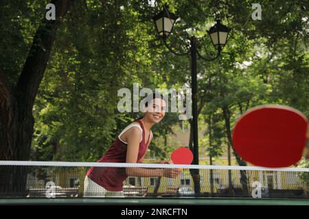 Jeune femme jouant au ping-pong dans le parc Banque D'Images