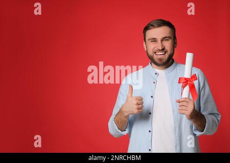 Heureux étudiant avec diplôme sur fond rouge. Espace pour le texte Banque D'Images
