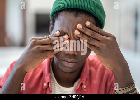 Homme noir fatigué se sentir étourdi de travail excessif manque de fatigue oculaire de sommeil épuisé après une longue utilisation de l'ordinateur portable Banque D'Images