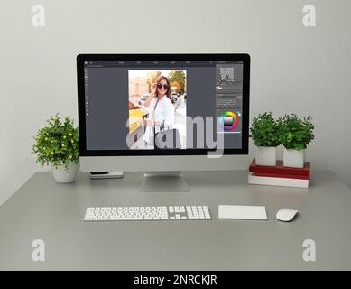 Le lieu de travail du concepteur. Ordinateur avec application photo Editor sur table Banque D'Images