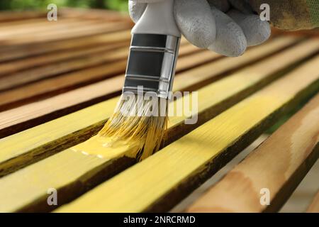 Ouvrier peinture surface en bois avec teinture jaune à l'extérieur, gros plan Banque D'Images