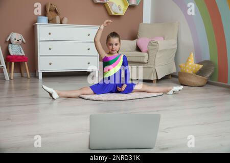 Mignonne petite fille se réchauffant avant le cours de danse en ligne à la maison Banque D'Images