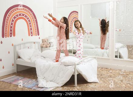 Jolies petites filles en pyjama jouant avec des plumes sur le lit à la maison. Bonne enfance Banque D'Images