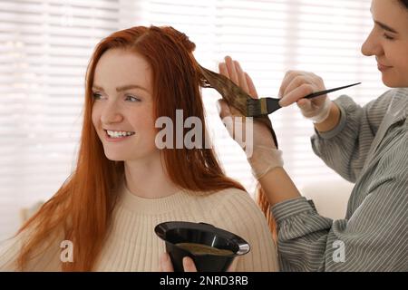 Coiffeur professionnel teint les cheveux de la femme avec le henné dans le salon de beauté Banque D'Images