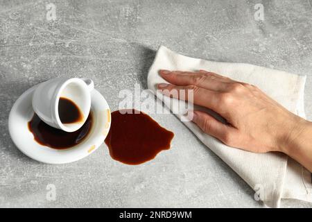 Femme essuyant du café renversé sur une table grise, gros plan Banque D'Images