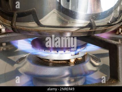 Jets de gaz bleus brûlant sous une casserole en acier sur une table de cuisson Banque D'Images