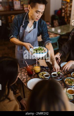 Serveur servant de la nourriture et des boulettes aux clients au restaurant Banque D'Images