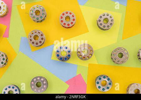 Bobines métalliques avec fil multicolore pour machine à coudre sur une table avec des notes adhésives en papier multicolore sur fond Banque D'Images