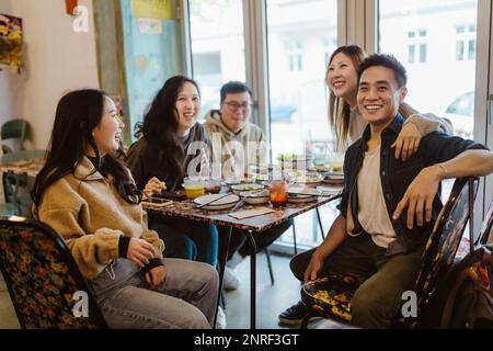 Des amis hommes et femmes heureux se sont réunis pendant le déjeuner au restaurant Banque D'Images