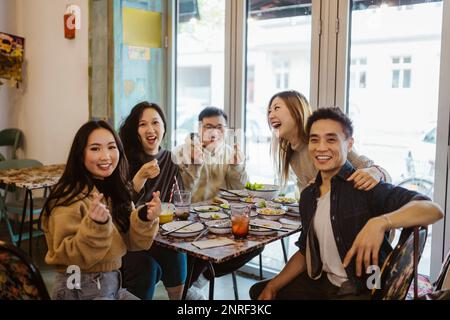 Des amis multiraciaux heureux, hommes et femmes, se réjouissant de rire pendant le déjeuner au restaurant Banque D'Images