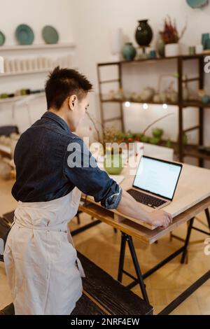 Homme potter travaillant sur un ordinateur portable lorsqu'il est debout à l'atelier Banque D'Images