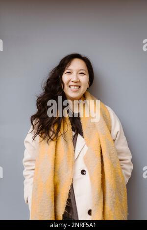 Portrait d'une femme heureuse portant des vêtements chauds sur fond gris Banque D'Images