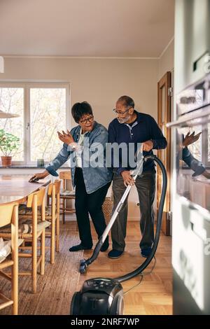 Couple senior s'amusant pendant le nettoyage de la maison Banque D'Images