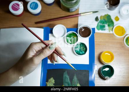La main de femme plonge une brosse dans la peinture Banque D'Images