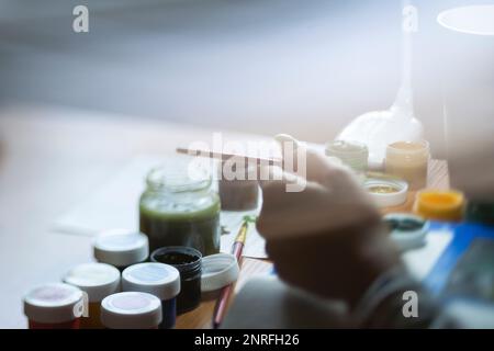 La main de femme plonge une brosse dans la peinture Banque D'Images