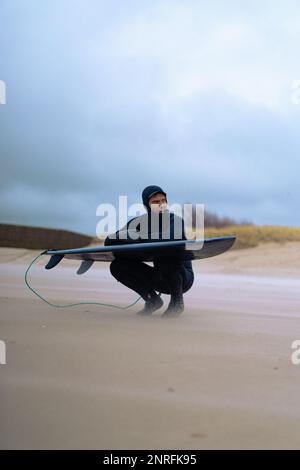 Surf à Kamchatka. Homme dans une combinaison avec une planche de surf sur les s. Banque D'Images