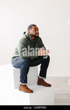 Homme noir mature et élégant assis sur des marches à l'intérieur Banque D'Images