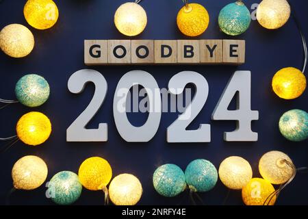 Lettre à l'alphabet Au revoir 2024 avec boule en coton, décoration LED sur fond bleu Banque D'Images